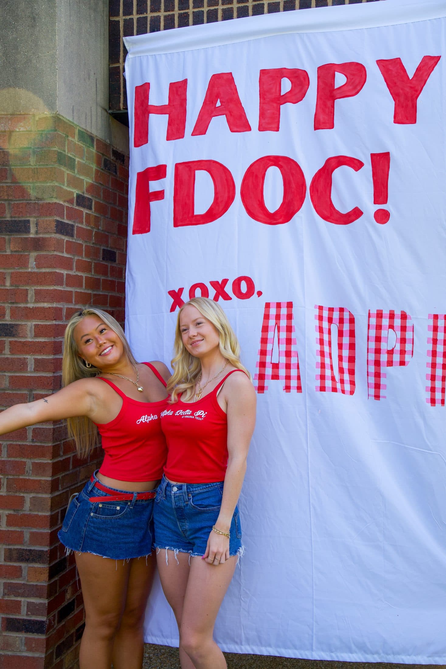 Two friends in red tanks celebrating under a hand-painted first-day banner