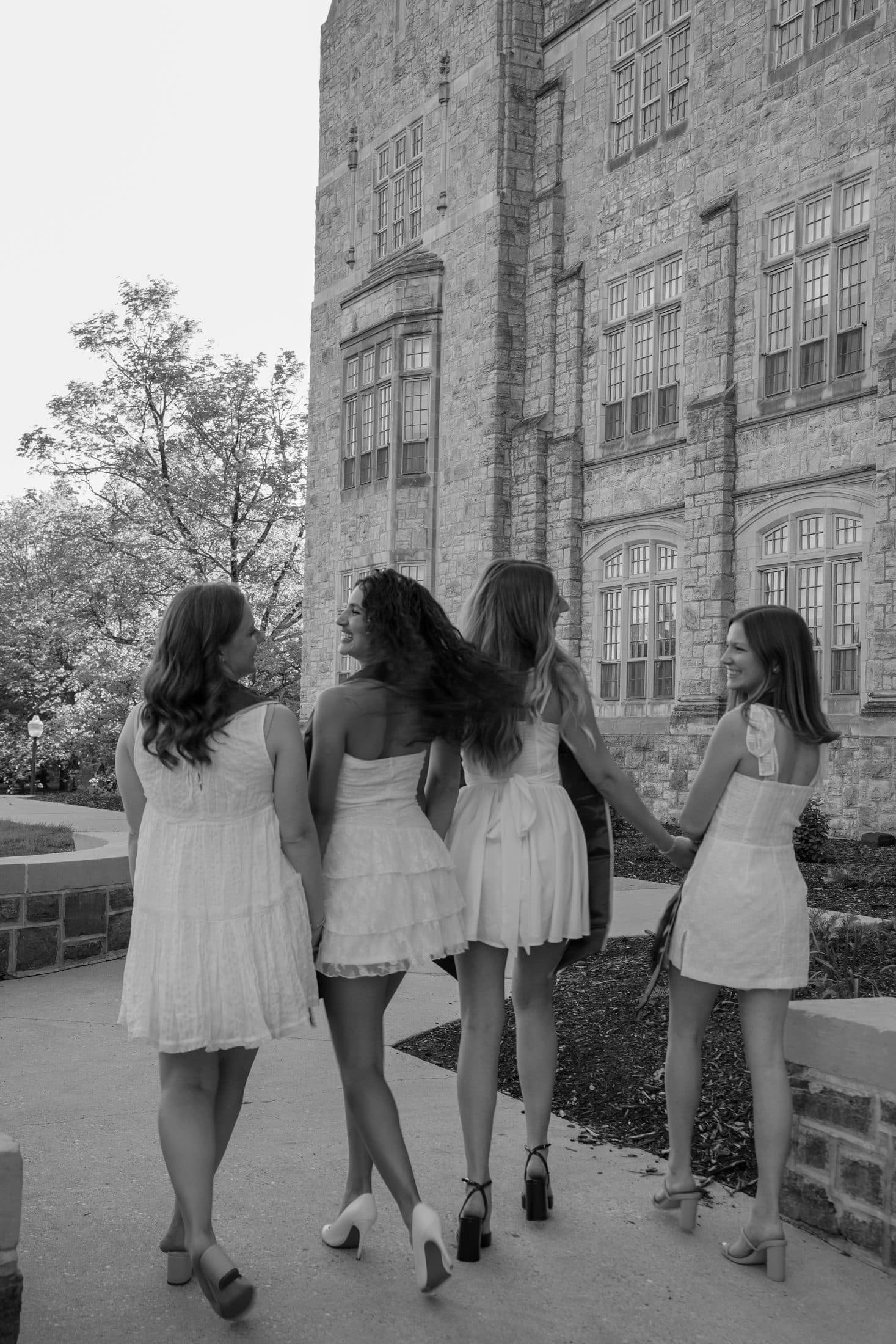 Four friends walking away together across campus in black and white