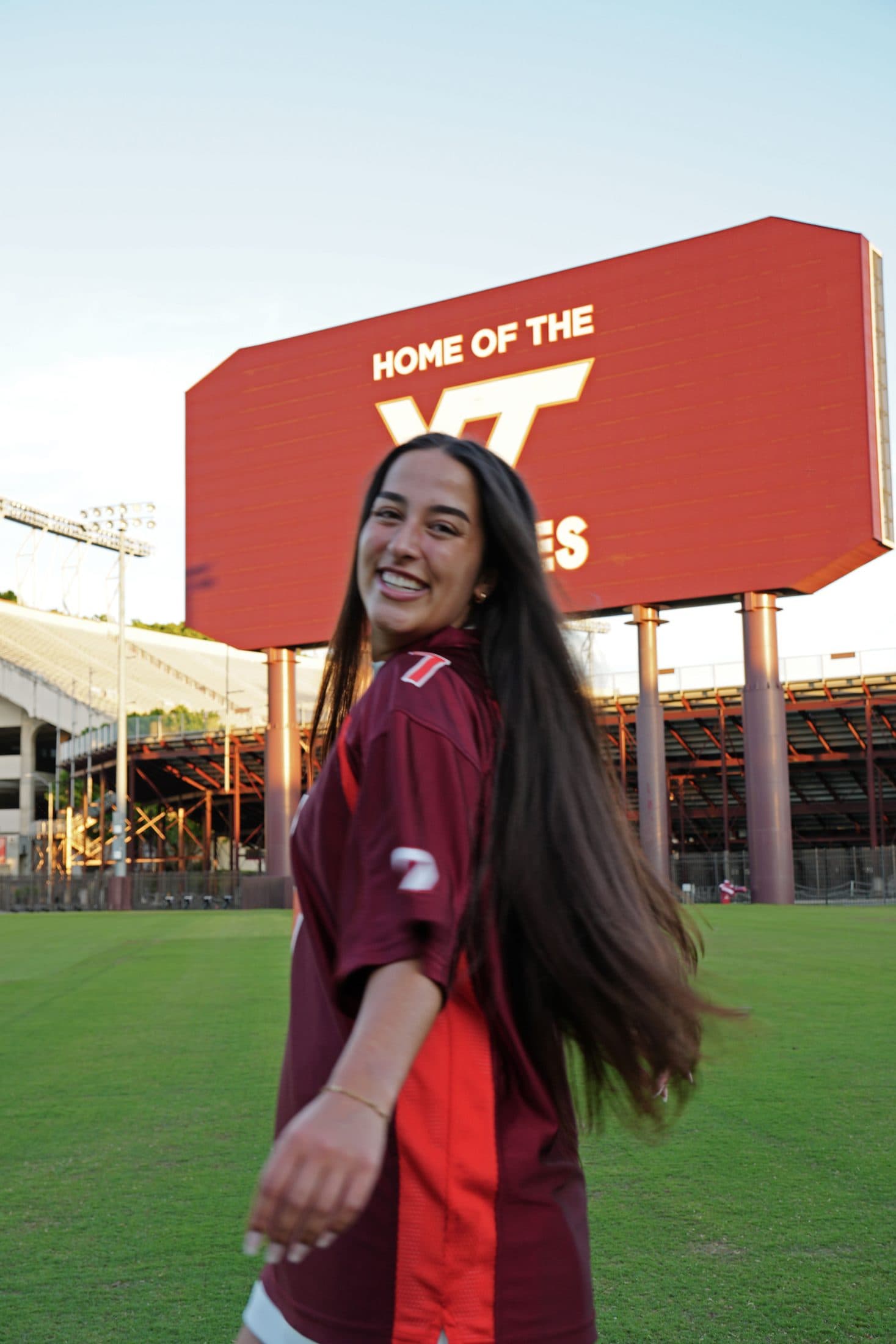 A graduate in a Virginia Tech jersey and skirt out on the football field